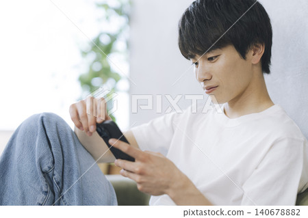 A young man looking at the screen of a smartphone A young man looking at the screen of a smartphone 140678882