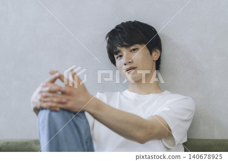A man in his 20s wearing a white T-shirt is looking directly at the camera. 140678925