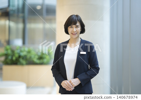 一位六十多歲的女商人面帶微笑,直視鏡頭,她的肖像照。 一位六十多歲的女商人面帶微笑,直視鏡頭,她的肖像照。 140678974