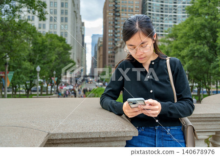 Young woman engaging with mobile device in a vibrant urban setting showcasing the harmony of technology and city living Young woman engaging with mobile device in a vibrant urban setting showcasing the harmony of technology and city living 140678976