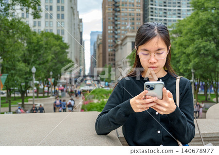 Young woman engaging with mobile device in a vibrant urban setting showcasing the harmony of technology and city living Young woman engaging with mobile device in a vibrant urban setting showcasing the harmony of technology and city living 140678977