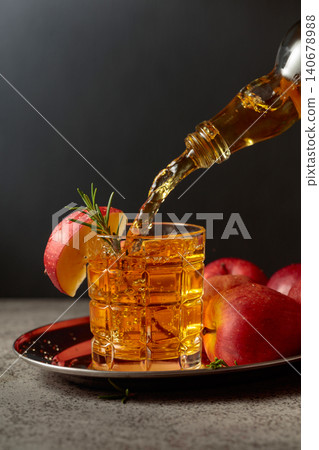 Apple cider is poured from a bottle into a glass. Apple cider is poured from a bottle into a glass. 140678988