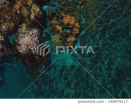 An aerial photograph showing the rocky shores, seaweed, and clear waters along the coast of Yagishiri Island. An aerial photograph showing the rocky shores, seaweed, and clear waters along the coast of Yagishiri Island. 140679117