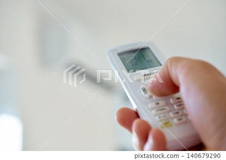 Hand pressing air conditioner remote control button 140679290