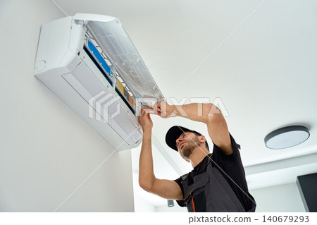 Technician servicing air conditioner at home Technician servicing air conditioner at home 140679293