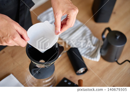 Hands placing paper filter in coffee dripper Hands placing paper filter in coffee dripper 140679305