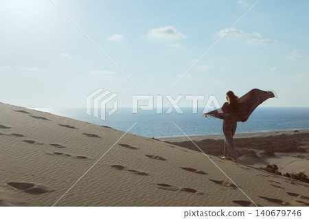 Woman walks along golden sand dunes at Patara Beach, Turkey, enjoying open space and sea views. Inspiring travel moment highlighting freedom, exploration and coastal tourism. Woman walks along golden sand dunes at Patara Beach, Turkey, enjoying open space and sea views. Inspiring travel moment highlighting freedom, exploration and coastal tourism. 140679746