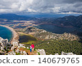 Young mother and son stand on mountain viewpoint above Dalyan, Turkey, overlooking river delta, lagoon, Iztuzu Turtle beach. Scenic travel moment highlighting family adventure and nature exploration. 140679765