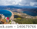 Young mother and son stand on mountain viewpoint above Dalyan, Turkey, overlooking river delta, lagoon, Iztuzu Turtle beach. Scenic travel moment highlighting family adventure and nature exploration. 140679766