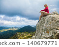 Woman sits on a rocky cliff above Dalyan, Turkey, overlooking sea,  Iztuzu Turtle beach, river delta and lagoon. Inspiring travel scene with panoramic coastal landscape and outdoor lifestyle. 140679771