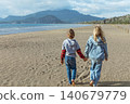 Young boy and girl walk hand in hand along Iztuzu Turtle Beach near Dalyan, Turkey. Warm family travel moment with wide sandy coast, sea views and relaxed summer lifestyle. 140679779