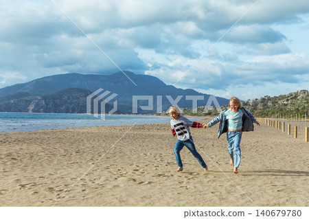 Boy and girl run and jump on Iztuzu Beach near Dalyan, Turkey. Joyful family travel moment with active lifestyle, sandy coast and carefree childhood by the sea. Boy and girl run and jump on Iztuzu Beach near Dalyan, Turkey. Joyful family travel moment with active lifestyle, sandy coast and carefree childhood by the sea. 140679780