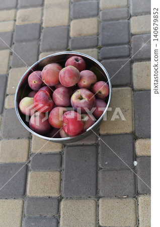 Metal bowl filled with ripe red apples resting on cobblestone floor. Metal bowl filled with ripe red apples resting on cobblestone floor. 140679852