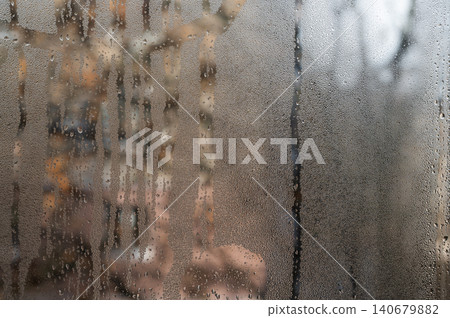 condensation covers a wet glass pane. Thick droplets slide slowly, leaving winding trails. wet glass. abstract background. condensation covers a wet glass pane. Thick droplets slide slowly, leaving winding trails. wet glass. abstract background. 140679882