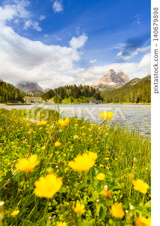 Colorful wildflowers on the shore of Lake Misurina with the iconic Tre Cime di Lavaredo rising above alpine forests in the background. Scenic summer landscape in the Dolomites, northern Italy. Colorful wildflowers on the shore of Lake Misurina with the iconic Tre Cime di Lavaredo rising above alpine forests in the background. Scenic summer landscape in the Dolomites, northern Italy. 140679898