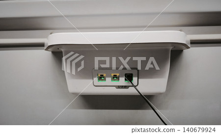 Closeup of power outlet on train wall. Three sockets and charging port are visible, 140679924