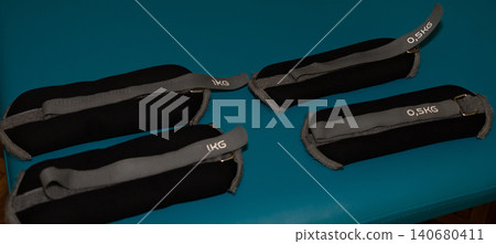 Weighted ankle cuffs and training straps for physical therapy and fitness on a blue surface. Weighted ankle cuffs and training straps for physical therapy and fitness on a blue surface. 140680411