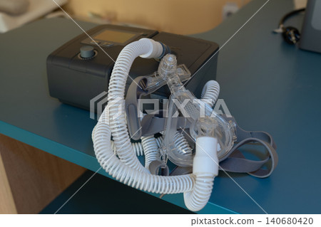 Medical CPAP machine and nasal mask with breathing tube on table for sleep apnea treatment. Medical CPAP machine and nasal mask with breathing tube on table for sleep apnea treatment. 140680420