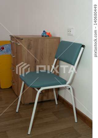 Minimalist teal folding chair positioned near a wooden dresser in a bright modern room. Minimalist teal folding chair positioned near a wooden dresser in a bright modern room. 140680449