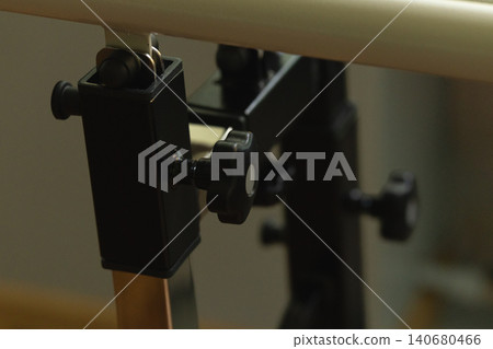 Close up of a black metal clamp securing a silver rod in an industrial laboratory equipment assembly. Close up of a black metal clamp securing a silver rod in an industrial laboratory equipment assembly. 140680466