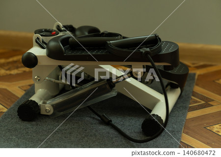White and black stepper machine for home fitness and aerobic exercise on gray mat White and black stepper machine for home fitness and aerobic exercise on gray mat 140680472
