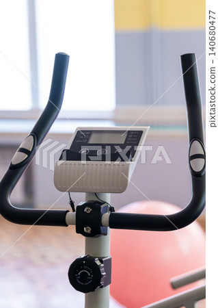 Close up of stationary exercise bike handlebar and digital display monitor in bright fitness gym. Close up of stationary exercise bike handlebar and digital display monitor in bright fitness gym. 140680477