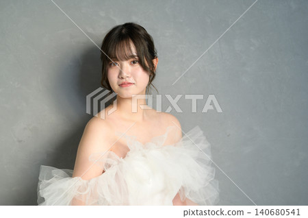 一位身穿白色婚紗的日本女子在灰色背景下微笑。 一位身穿白色婚紗的日本女子在灰色背景下微笑。 140680541