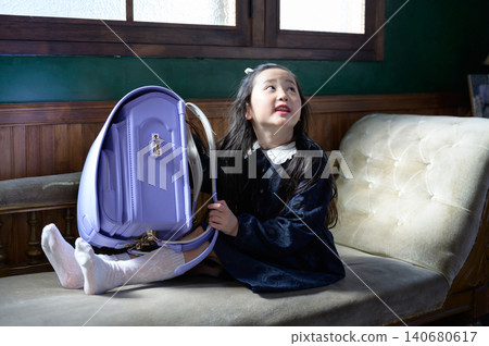 A Japanese girl with a schoolbag sitting on a sofa A Japanese girl with a schoolbag sitting on a sofa 140680617