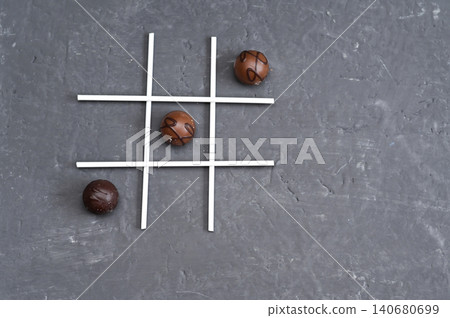 Chocolate balls placed in tic tac toe layout using white lines on dark surface. Chocolate balls placed in tic tac toe layout using white lines on dark surface. 140680699