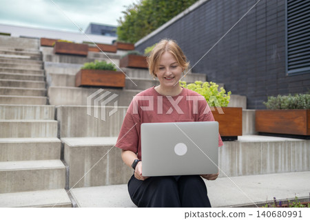 Young woman working on laptop on outdoor city stairs Young woman working on laptop on outdoor city stairs 140680991