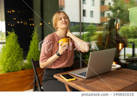 Tired young woman touching neck with pain while working on laptop Tired young woman touching neck with pain while working on laptop 140681018