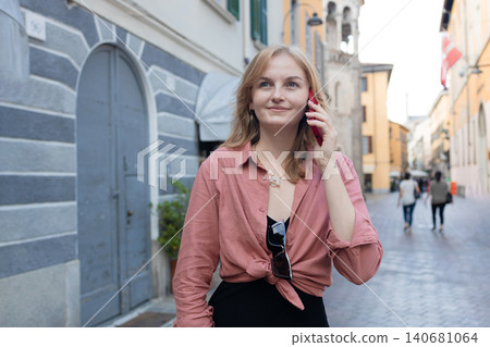 Happy young woman talking on smartphone on beautiful European city street Happy young woman talking on smartphone on beautiful European city street 140681064