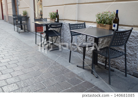 Cozy outdoor cafe terrace with tables and wine bottles on a European street Cozy outdoor cafe terrace with tables and wine bottles on a European street 140681085