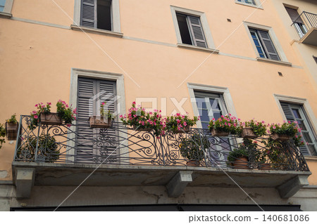 Traditional European building facade with a cozy balcony filled with blooming flowers Traditional European building facade with a cozy balcony filled with blooming flowers 140681086