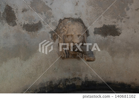 Vintage stone lion head water spout on an old wall Vintage stone lion head water spout on an old wall 140681102