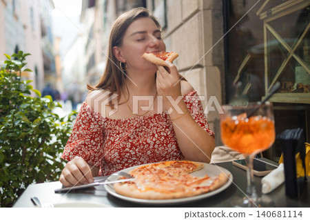 Happy young woman eating delicious Italian pizza at outdoor cafe in Europe Happy young woman eating delicious Italian pizza at outdoor cafe in Europe 140681114