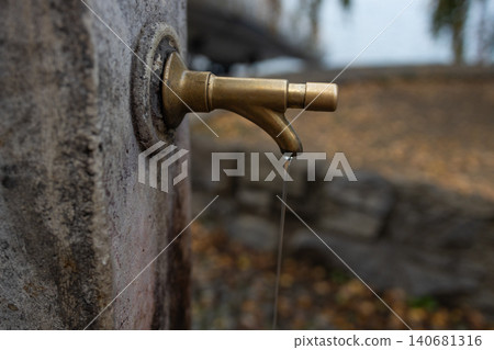 Old brass water tap on a stone fountain Old brass water tap on a stone fountain 140681316