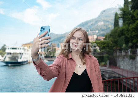 Young woman taking a selfie on the Lake Como waterfront Young woman taking a selfie on the Lake Como waterfront 140681325