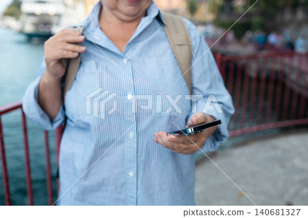 Happy senior woman tourist holding a smartphone at Lake Como 140681327