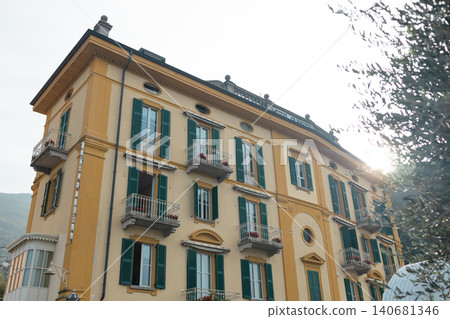 Picturesque street view featuring a luxury historic residential building with decorative stone facade elements under a blue sky at a famous European lake resort. Picturesque street view featuring a luxury historic residential building with decorative stone facade elements under a blue sky at a famous European lake resort. 140681346