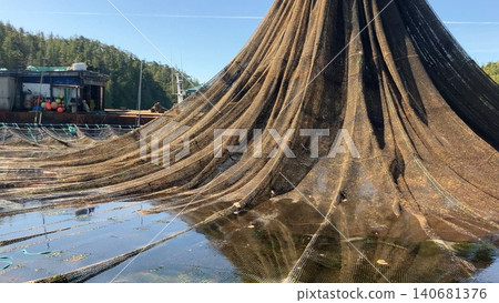 Crane lifting aquaculture net at fish farm 140681376