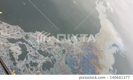 Iridescent oil slick polluting dark water surface 140681377