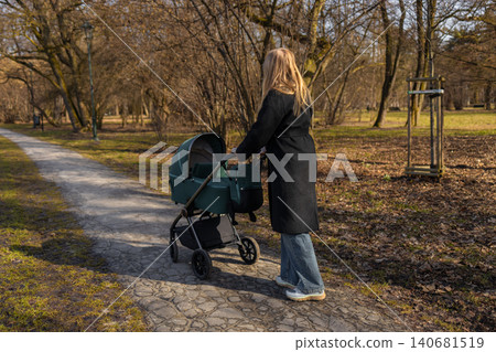 30s mother woman walking along park path while pushing baby stroller, enjoying sunny day and outdoor parenting lifestyle. 30s mother woman walking along park path while pushing baby stroller, enjoying sunny day and outdoor parenting lifestyle. 140681519