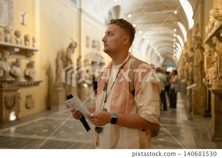 Male tourist with map exploring sculpture gallery in historical museum Male tourist with map exploring sculpture gallery in historical museum 140681530