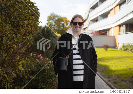 Happy pregnant woman walking on street of modern residential area 140681537