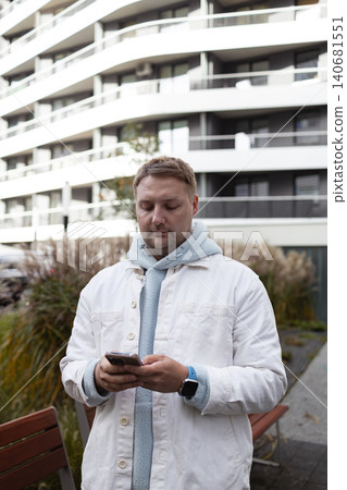 Man using smartphone near modern residential building Man using smartphone near modern residential building 140681551