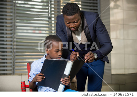 Businessman reading a book to his child outdoors 140681571