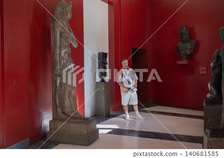 Male tourist exploring ancient Egyptian exhibition in museum gallery Male tourist exploring ancient Egyptian exhibition in museum gallery 140681585