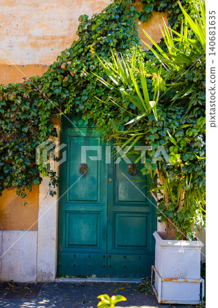 Ancient green wooden door framed by lush climbing ivy on an old building facade. Ancient green wooden door framed by lush climbing ivy on an old building facade. 140681635