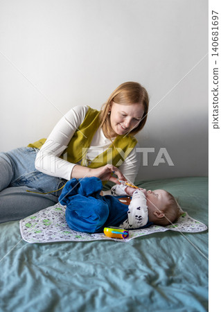 Young mother taking care of her baby boy on a bed at home. 140681697
